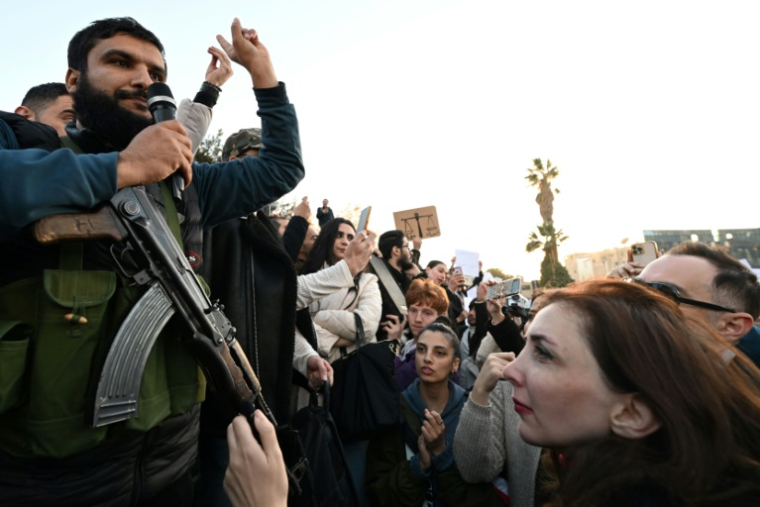 Un ex-rebelle s'adresse à des manifestants prodémocratie, sur la place des Omeyyades à Damas le 19 décembre 2024 ( AFP / LOUAI BESHARA )