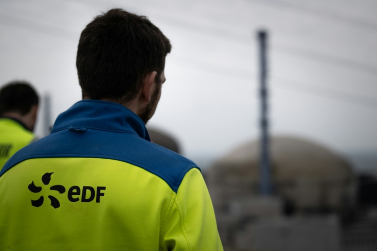 Des employés d'EDF en face d'une coupole de la centrale nucléaire de Flamanville dans la Manche, le 25 avril 2024 ( AFP / Lou BENOIST )