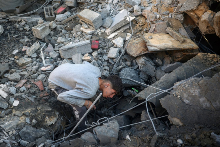 Une jeune personne fouille les décombres d'un bâtiment détruit par une frappe israélienne à Deir al-Balah, dans le centre de la bande de Gaza, le 22 décembre 2024 ( AFP / Eyad BABA )