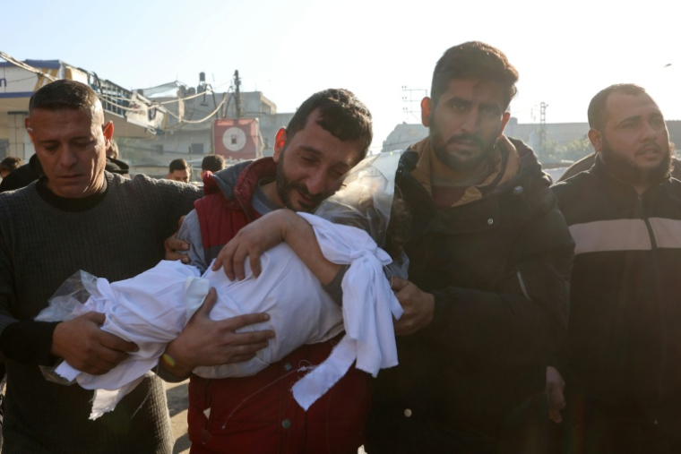 Un homme porte le corps d'un enfant, le 21 décembre 2024 à Jabalia dans le nord de la bande de Gaza ( AFP / Omar AL-QATTAA )