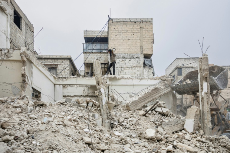 Un jeune marche près des décombres d'un bâtiment détruit dans la ville de Douma, dans la banlieue est de Damas, le 22 décembre 2024 ( AFP / Sameer Al-DOUMY )