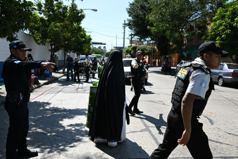 Des policiers et des membres de la secte juive ultra-orthodoxe Lev Tahor devant le centre où sont pris en charge 160 enfants secourus par les autorités, le 22 décembre 2024 à Guatemala ( AFP / Johan ORDÓÑEZ )