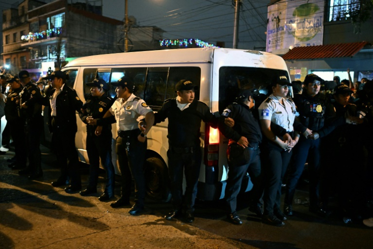 Des policiers guatémaltèques protègent un minibus transportant des enfants exfiltrés d'une propriété d'une secte juive ultra-orthodoxe, le 22 décembre 2024 ( AFP / Johan ORDÓÑEZ )