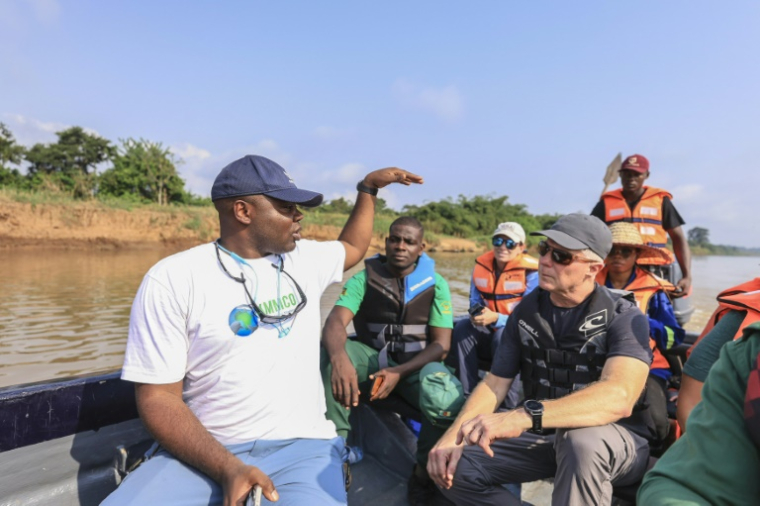 Aristide Takoukam Kamla (g), docteur en biologie marine, spécialiste du lamantin d'Afrique, s'entretient avec des touristes et d'autres biologistes sur un bateau à Dizangue, le 10 décembre 2024 au Cameroun ( AFP / Daniel Beloumou Olomo )