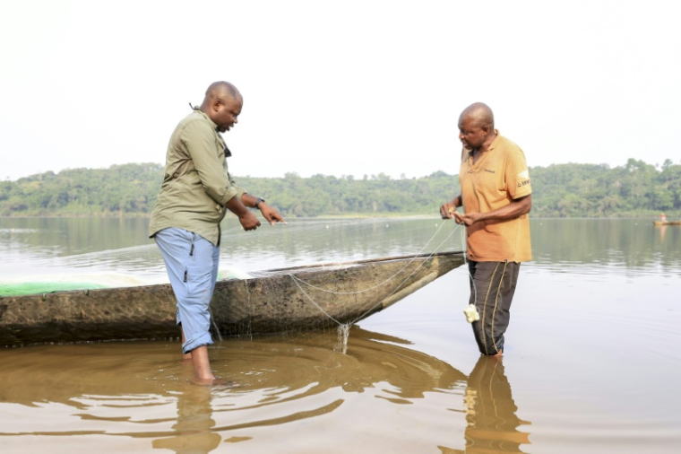 Aristide Takoukam Kamla (g), docteur en biologie marine, spécialiste du lamantin d'Afrique, parle avec un pêcheur à Dizangue, le 11 décembre 2024 au Cameroun ( AFP / Daniel Beloumou Olomo )