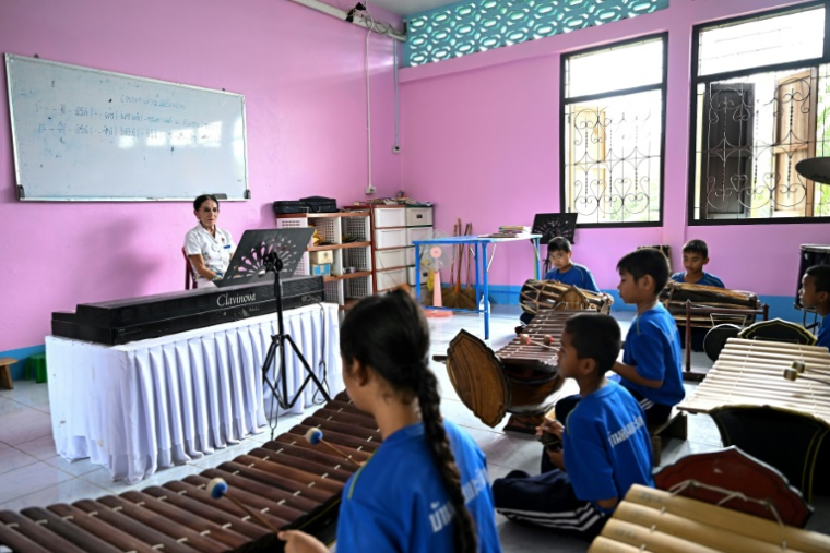 Elisabeth Zana donne un cours de musique aux élèves de l'école Bankuankojan de Krabi, également connue sous le nom d'"école Natacha", en mémoire de sa fille Natacha décédée lors du tsunami de 2004, le 22 novembre 2024 en Thaïlande ( AFP / Manan VATSYAYANA )