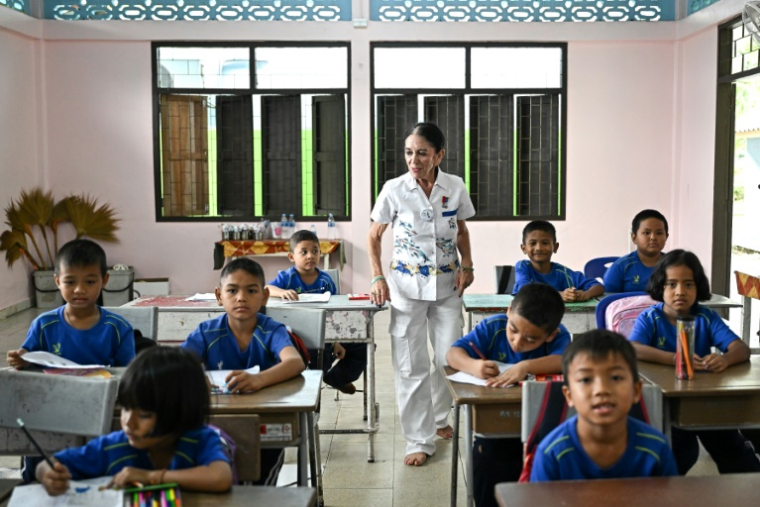 Elisabeth Zana dans une salle de classe avec les élèves de l'école Bankuankojan de Krabi, également connue sous le nom d'"école Natacha", en mémoire de sa fille Natacha décédée lors du tsunami de 2004, le 22 novembre 2024 en Thaïlande ( AFP / Manan VATSYAYANA )