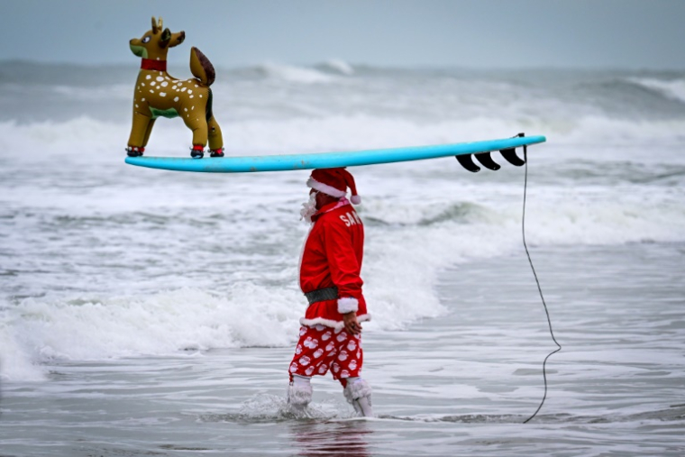 Un surfeur déguisé en Père Noël, le 24 décembre 2024 à Cocoa Beach, en Floride ( AFP / Giorgio VIERA )