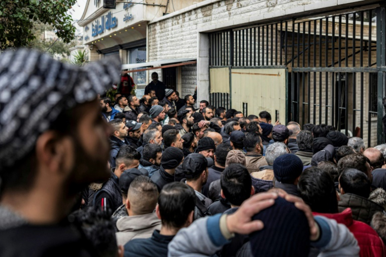 Des hommes attendent devant un centre du gouvernement de transition pour la remise d'armes légères et l'enregistrement des anciens soldats, policiers et civils à Damas, le 24 décembre 2024, en Syrie ( AFP / Sameer Al-DOUMY )