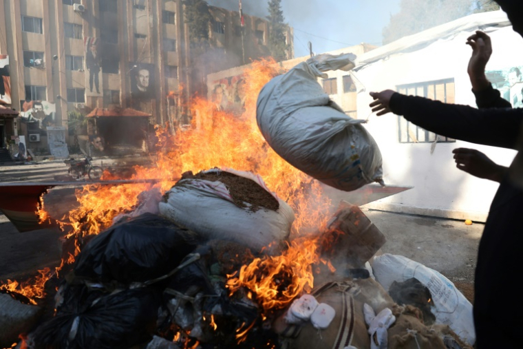 Un homme jette un sac sur une pile de drogues en feu, à Damas, le 25 décembre 2024 ( AFP / OMAR HAJ KADOUR )