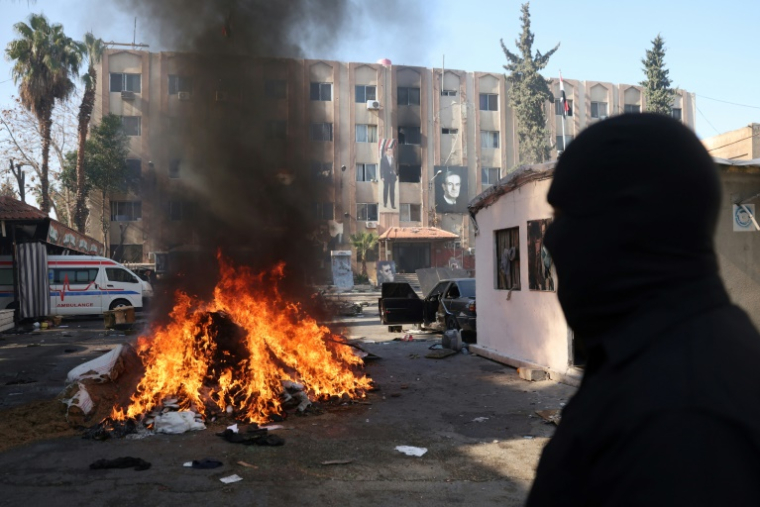 Un homme regarde un tas de drogues brûler, à Damas, le 25 décembre 2024 ( AFP / OMAR HAJ KADOUR )