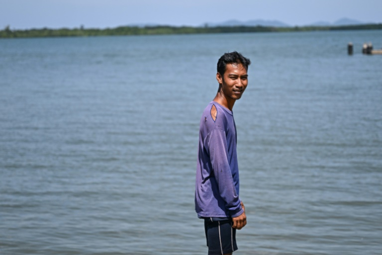 Pirun Kla-Talay, qui a perdu ses parents dans le tsunami de 2004, debout sur une jetée dans le district de Bang Wa, dans la province de Phang Nga, le 19 novembre 2024 en Thaïlande ( AFP / Manan VATSYAYANA )