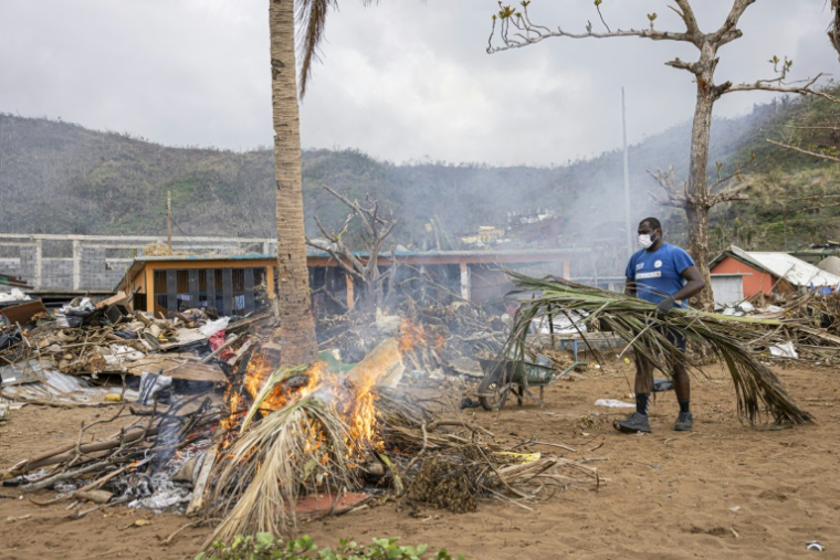 Un habitant de Mayotte fait brûler des branches de palmiers arrachées sur la plage à Acoua, le 25 décembre 2024 ( AFP / PATRICK MEINHARDT )