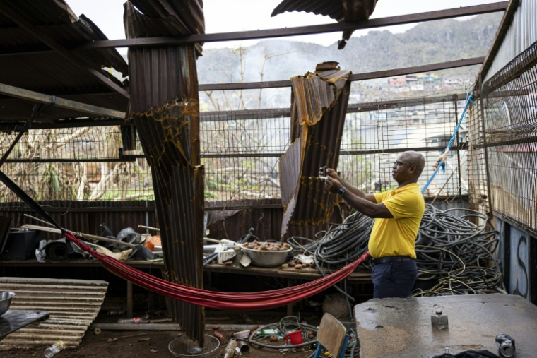 Un fonctionnaire prend une photo avec son téléphone portable pour évaluer les dégâts à l'intérieur d'une propriété à Acoua, plusieurs jours après le passage du cyclone Chido à Mayotte, le 25 décembre 2024 ( AFP / PATRICK MEINHARDT )