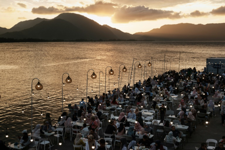 Des personnes attablées en bord de mer sur la terrasse d'un café construit sur le site où toutes les maisons ont été détruites par le tsunami de 2004 dans l'océan Indien, à Banda Aceh, le 25 décembre 2024, à la veille du 20e anniversaire de la catastrophe ( AFP / Yasuyoshi CHIBA )