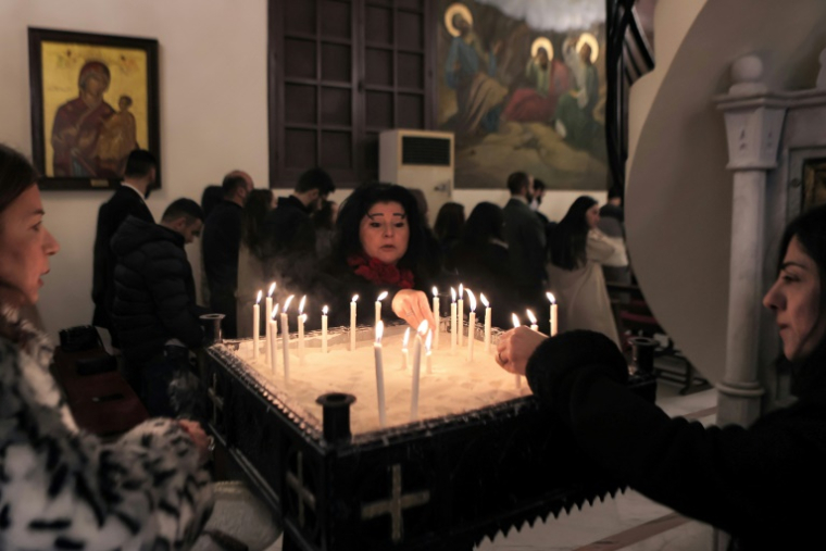 Des fidèles allument des bougies lors de la messe de Noël à la cathédrale grecque orthodoxe Saint-Georges à Lattaquié, dans l'ouest de la Syrie, le 25 décembre 2024 ( AFP / AAREF WATAD )