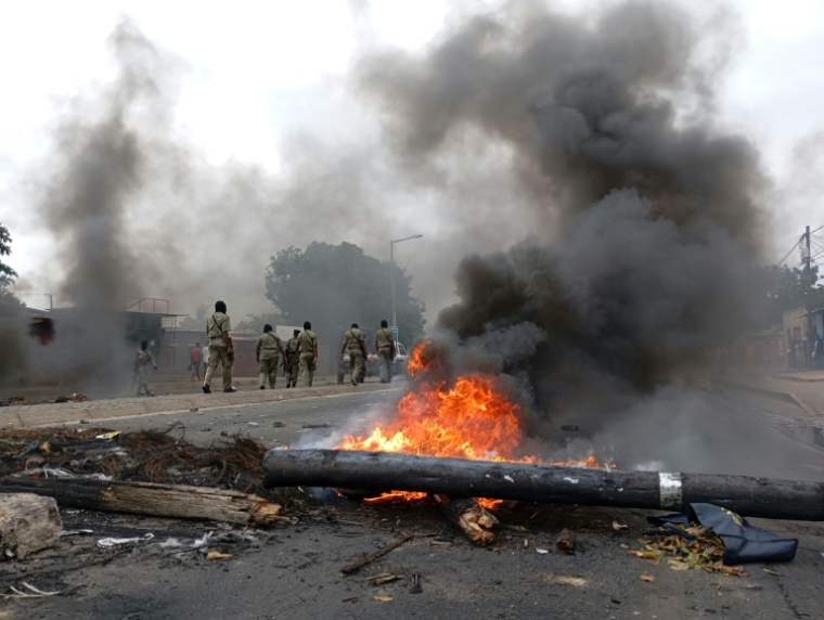 Des membres des forces de sécurité passent près d'une barricade en feu dans une rue de Maputo, le 24 décembre 2024 au Mozambique ( AFP / Amilton Neves )