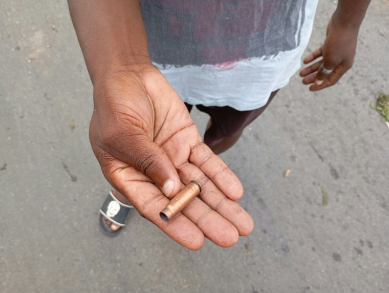 Un homme montre une douille de balle usagée dans une rue de Maputo, le 24 décembre 2024 au Mozambique ( AFP / Amilton Neves )